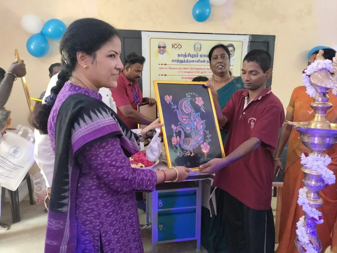 Hope Chennai student presenting a framed painting to a guest at an award function