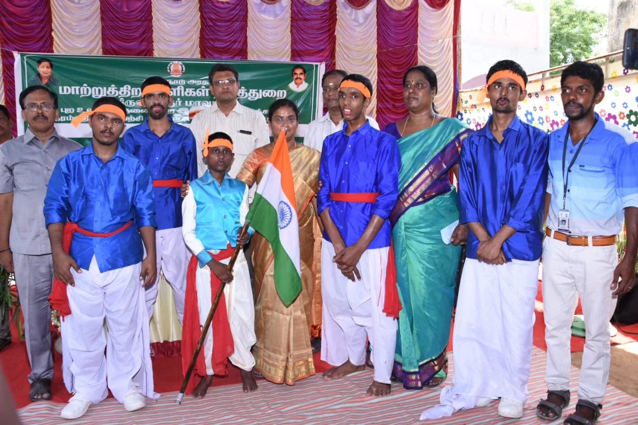 Students in costume holding the Indian flag at a disability welfare department event