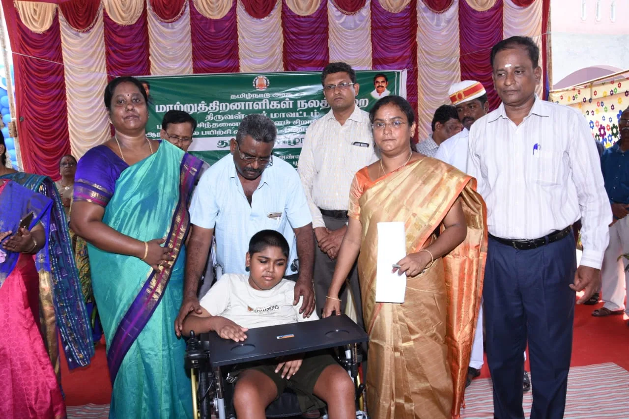 Child in a wheelchair with officials and Hope Chennai staff at a welfare event